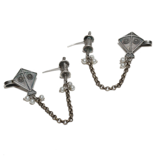 Pair of silver earrings with chain and pearl accents , kite motif on a white background