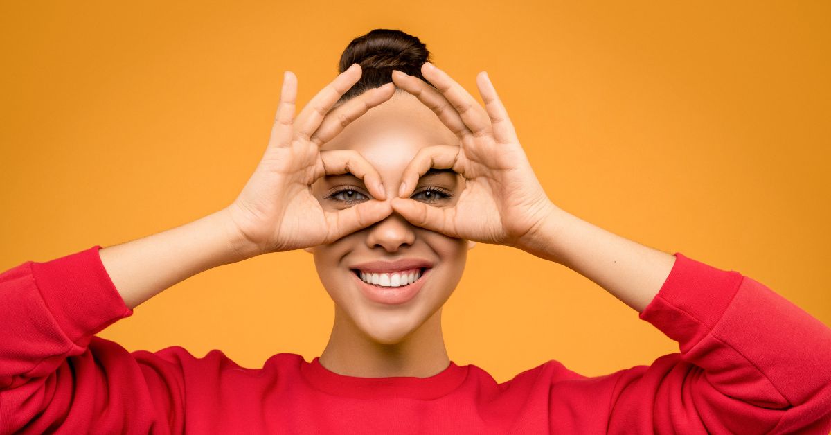 Women in red t-shirt looking for more bangles for her, see given expression by hand in binocular form with smile
