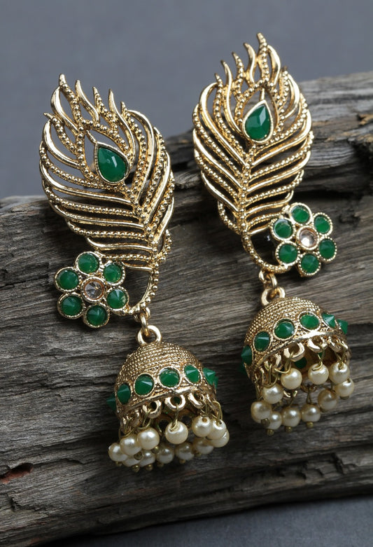 Bindhani peacock feather motif jhumka with green stone earrings kept on wooden piece.