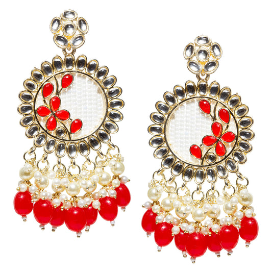 Pair of gold-plated traditional drop earrings featuring a circular kundan stone border around a white textured center with red floral accents. The earrings are embellished with pearl clusters and dangling red teardrop beads, creating a festive, ornate design. Displayed against a white background.