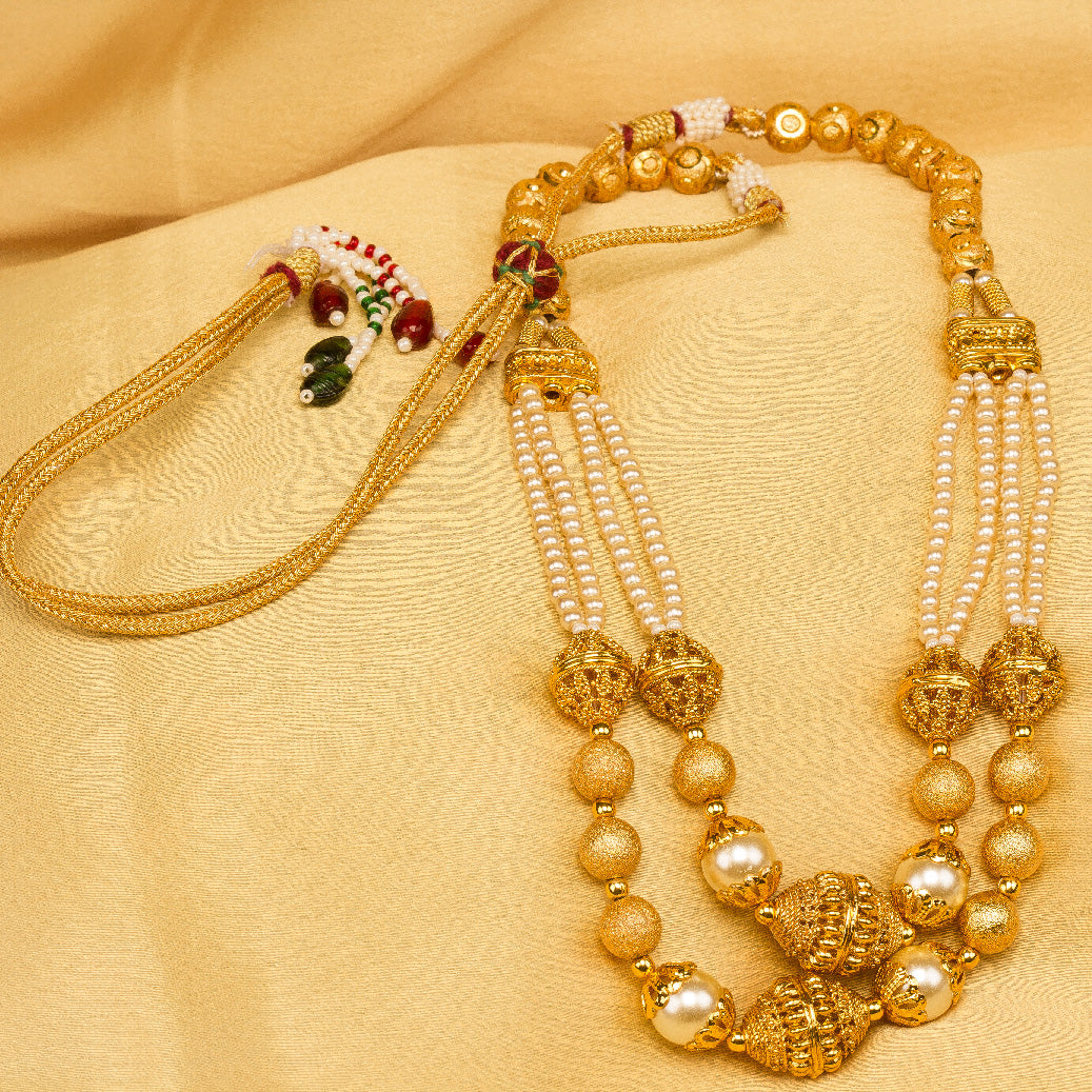Bindhani Gold-plated layered necklace with textured gold and pearl beads, golden cloth background