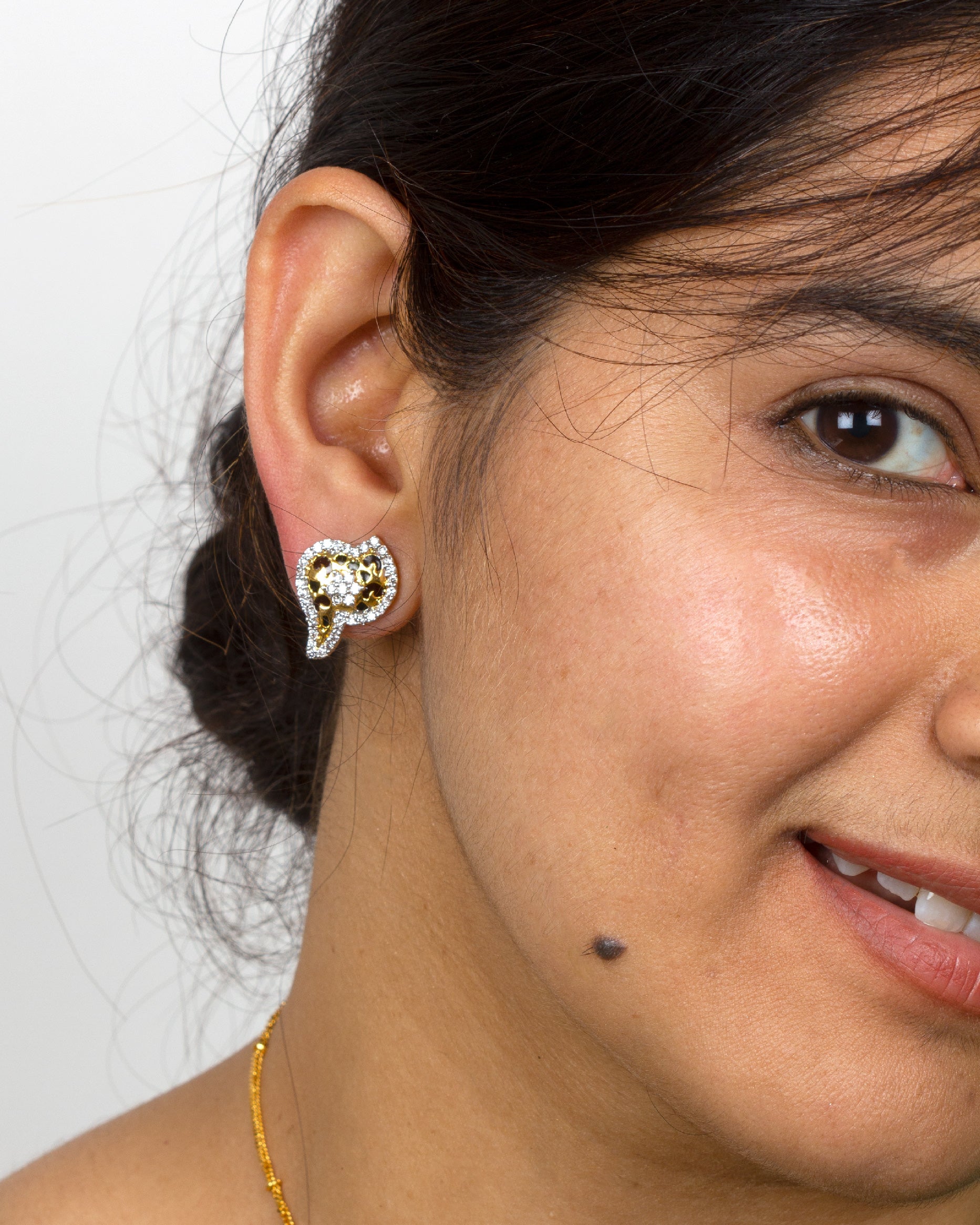 wearing a traditional gold-tone Bindhani Ad  stone stud 
earrings, featuring white stone detailing and elegant floral paisley design on a green ethnic outfit.