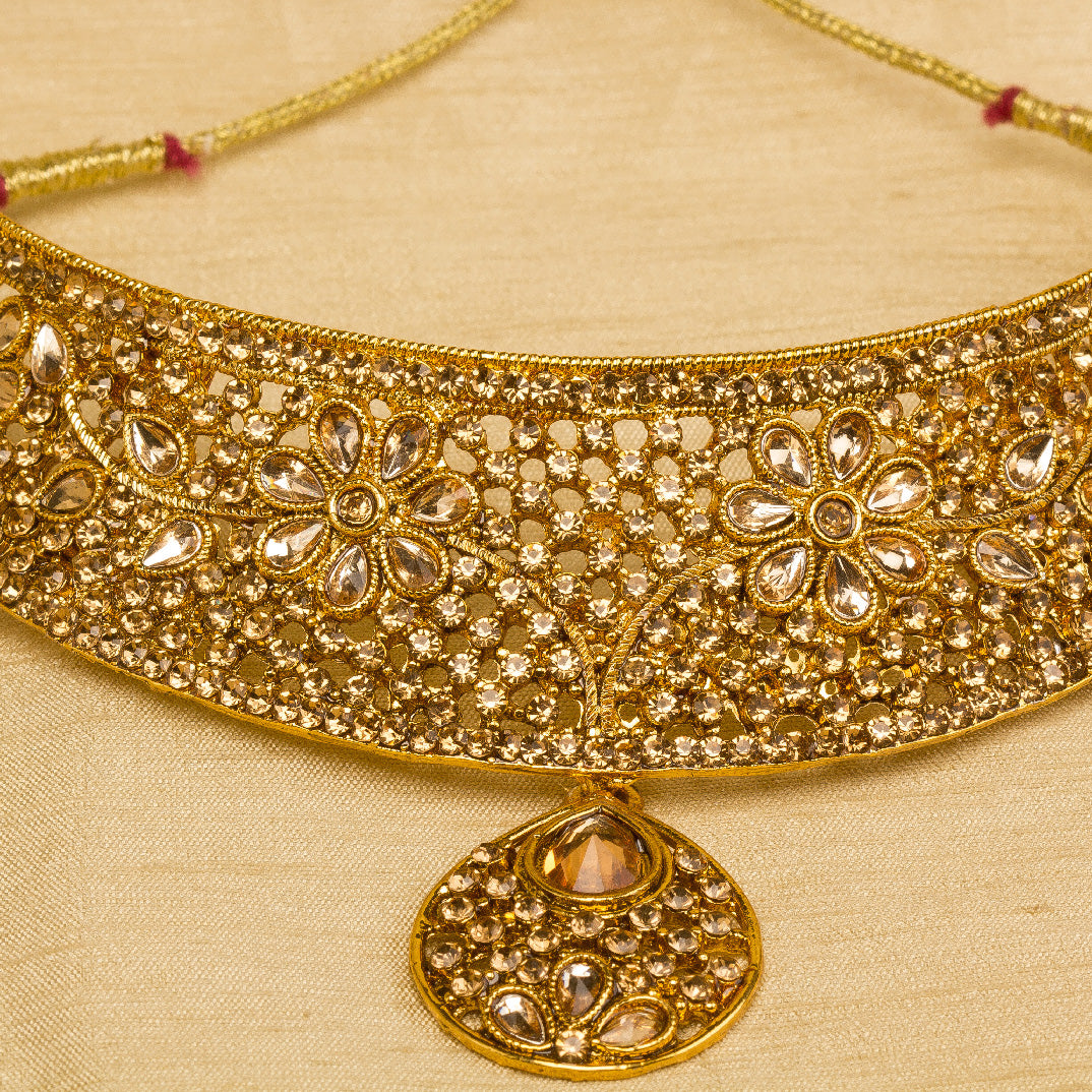 Bindhani gold-plated bridal necklace choker set for women featuring an intricate floral filigree choker design, brown sparkling stone embellishments,  statement necklace, on a grey background.