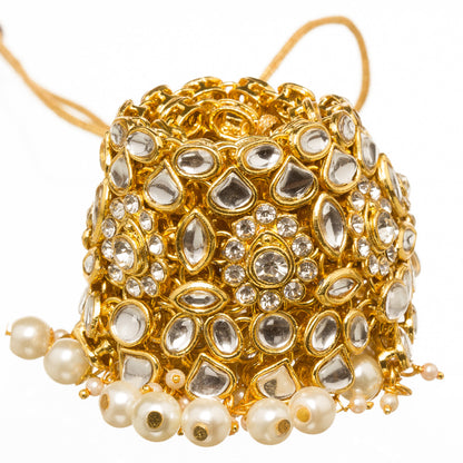 Close-up of gold-plated kundan-neklace choker with white pearl drops, white background