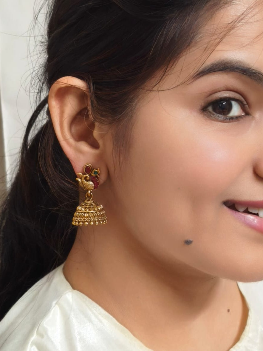 Bindhani gold-plated peacock jhumka earrings with pink and green stones and crystal accents for traditional ethnic wear.