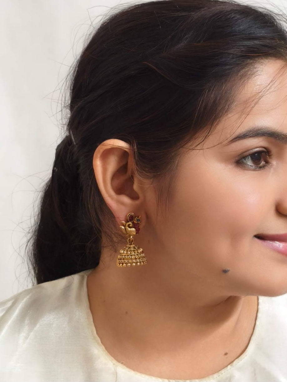 Bindhani gold-plated peacock jhumka earrings with pink and green stones and crystal accents for traditional ethnic wear.