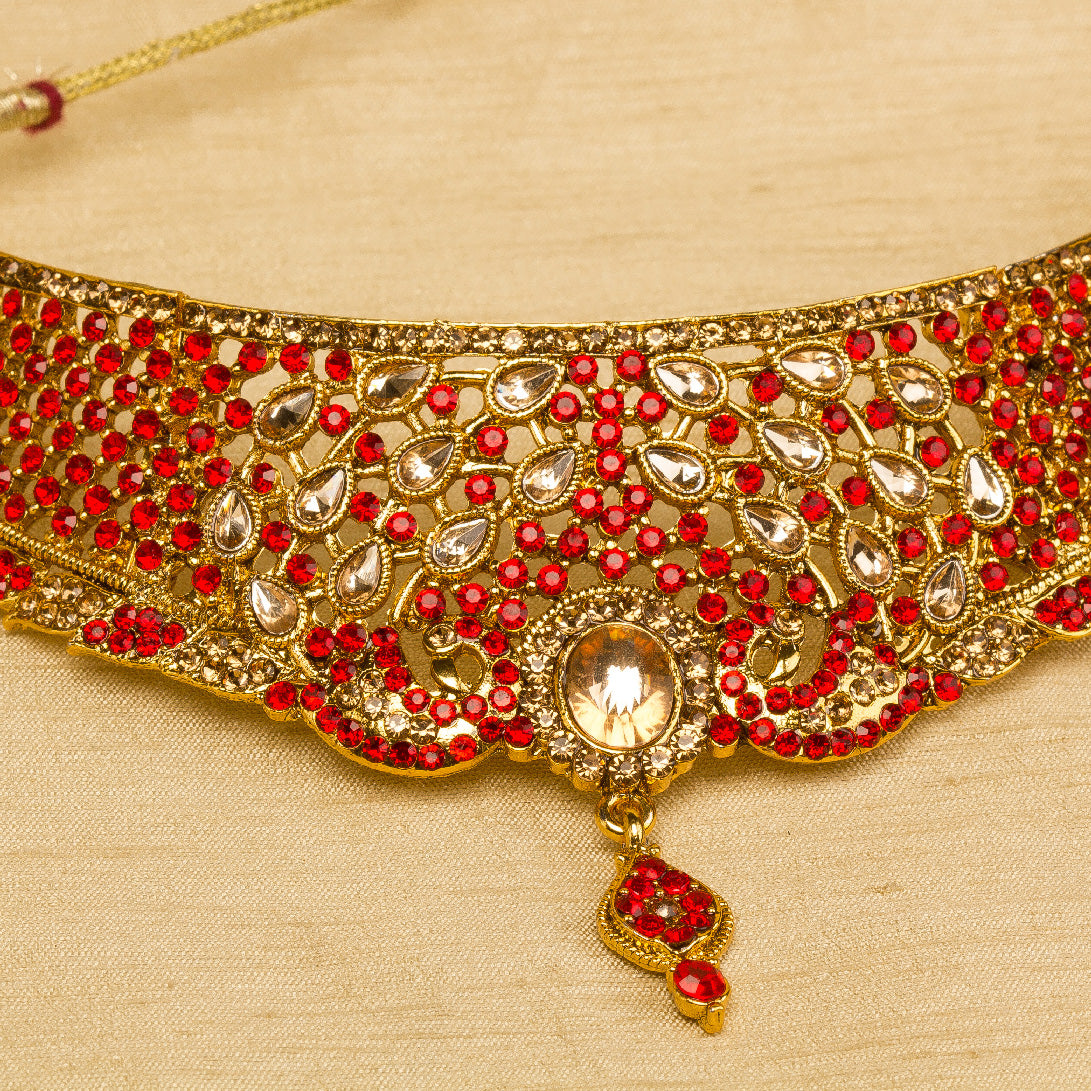 Bindhani gold-plated bridal choker necklace set for women featuring red stone, intricate floral detailing, a statement Nekalce, on a grey background."
