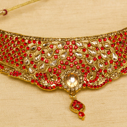 Bindhani gold-plated bridal choker necklace set for women featuring red stone, intricate floral detailing, a statement Nekalce, on a grey background."