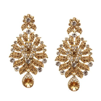 Bindhani gold-plated statement earrings featuring champagne and white stones, layered leaf motifs, intricate openwork detailing, floral accents, and a pear-shaped champagne stone drop. Displayed on a white background.