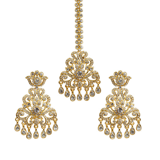 Bindhani gold plated white stone maang tikka and matching earrings set featuring an intricate floral and scrollwork design with sparkling white white stones. The statement earrings have a crown-inspired stud, ornate openwork pattern, a large round center stone, and seven teardrop-shaped dangling stone drops. The matching maang tikka features a decorative stone chain with an S hook,ornate centerpiece, and seven dangling stone drops.Traditional Indian bridal earrings tikka set displayed on a white background.