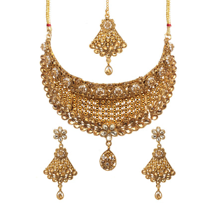 Bindhani gold-plated choker necklace set featuring intricate filigree lattice detailing, floral motifs, champagne stones, crystal embellishments, and a teardrop pendant. The set includes matching floral drop earrings and a coordinating maang tikka with teardrop danglers, displayed on a white background.