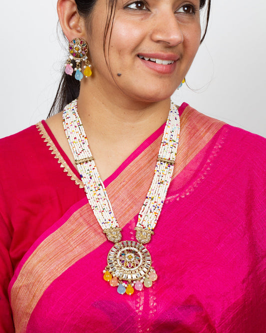 Woman wearing a Bindhani long Kundan stones Rani Haar pendant necklace set featuring intricate antique gold-plated craftsmanship with sparkling Kundan stones, traditional royal-inspired long necklace design, matching pendant, and coordinated earrings. Elegant ethnic jewelry set ideal for weddings, festive occasions, and bridal wear.