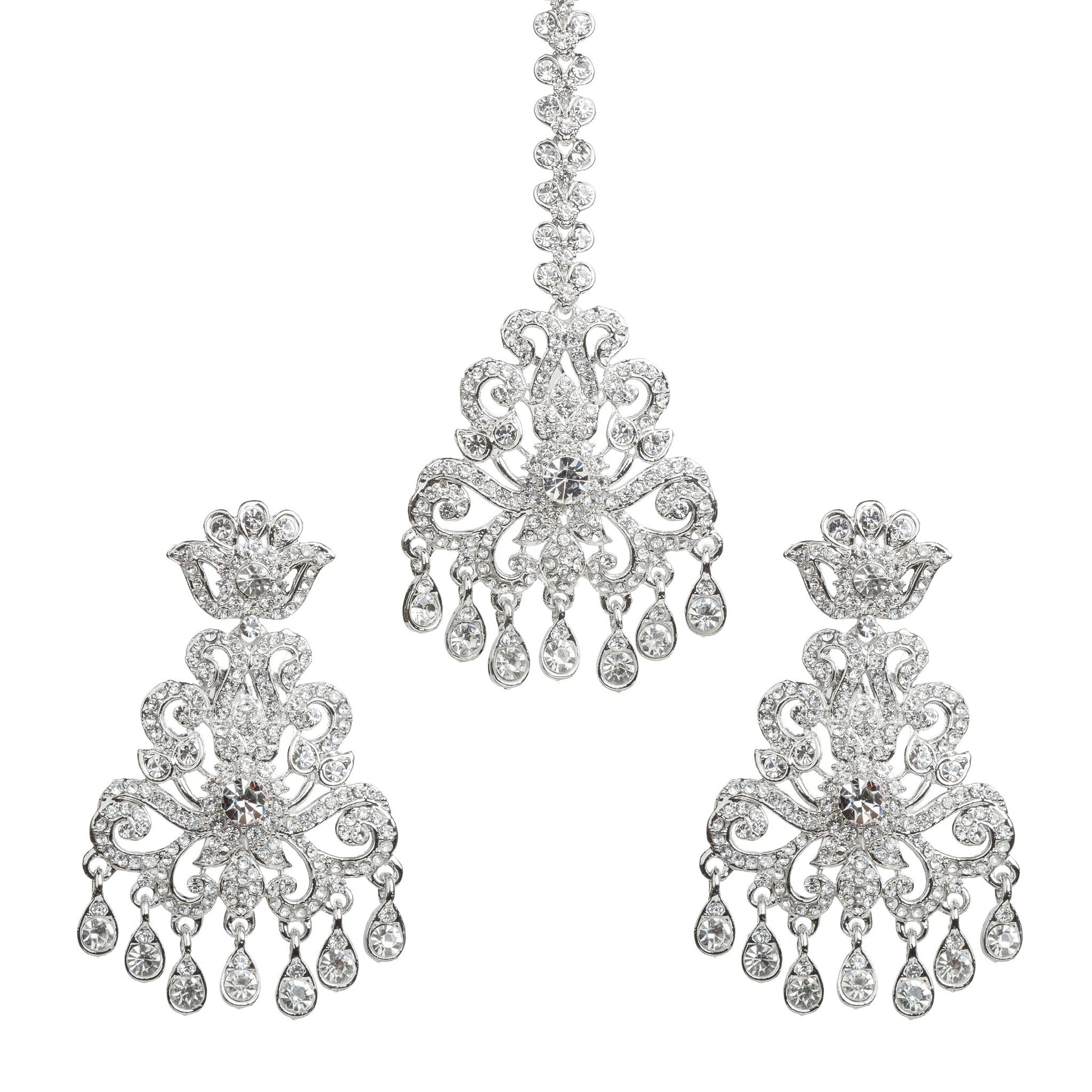 Bindhani silver plated white stone maang tikka and matching earrings set featuring an intricate floral and scrollwork design with sparkling white stones. The statement earrings showcase crown-inspired tops, detailed openwork patterns, a large central white stone, and multiple teardrop-shaped hanging white stone drops. The matching maang tikka features a decorative stone chain, ornate floral centerpiece, and dangling white stone accents. Traditional Indian bridal set displayed on a white background.