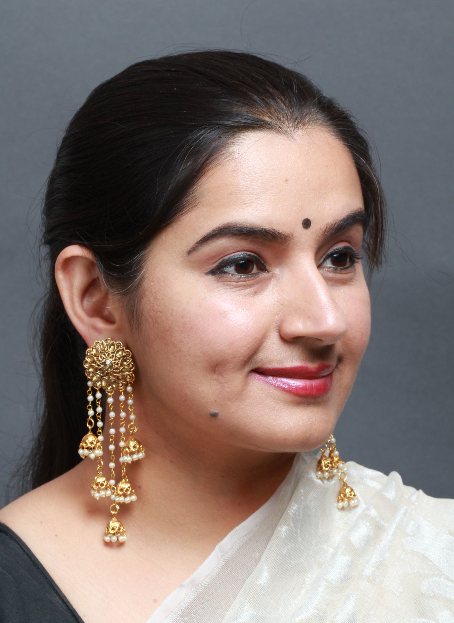 Woman wearing gold earrings with a plain background