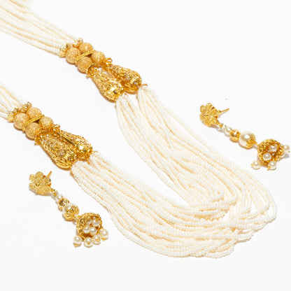 Bindhani gold-plated pearl mala necklace and earrings set featuring multiple strands of white pearls, intricate gold-tone floral detailing, decorative gold beads, traditional pendant accents, and matching pearl drop earrings. Elegant Indian ethnic jewelry set for women, perfect for bridal wear, weddings, festivals, and special occasions.