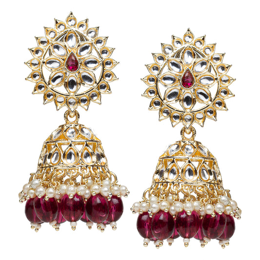 Bindhani Gold-plated jhumka earrings featuring a traditional dome-shaped design with kundan-style stone accents and a rich purple wine-colored drop detail. The upper stud section is embellished with decorative stones, leading to a rounded jhumka dome with intricate gold detailing. Below the dome, pearl and bead drops hang delicately, adding movement and elegance. The overall design combines kundan-inspired craftsmanship with pearl and colored accents for a festive, ethnic look.