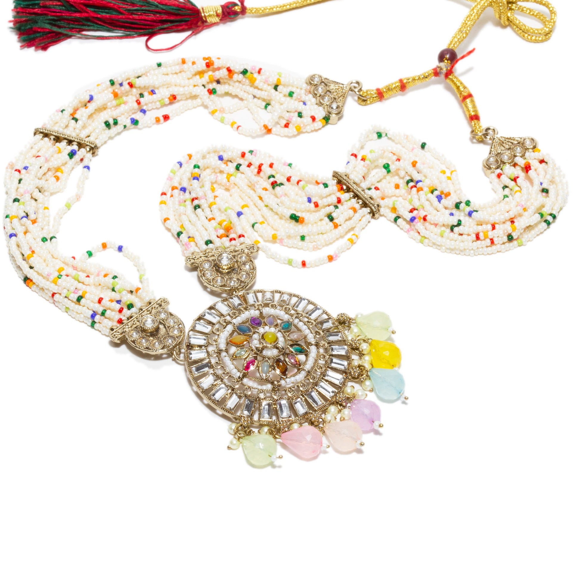 Traditional Bindhani-style rani haar necklace with multiple strands of white seed beads interspersed with small colorful beads in red, green, yellow, blue, and orange. The central circular pendant features intricate kundan work with a radial pattern of multicolored stones and dangling pastel teardrop-shaped beads in pink, yellow, mint green, and sky blue. The necklace is finished with antique gold-tone filigree accents and a red-and-green thread tassel at the clasp. elements are visible in this image