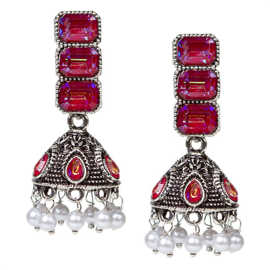 Bindhani oxidised silver-tone jhumki earrings with a vertical stud of three stacked maroon red rectangular stones in a silver frame. Below hangs a dome-shaped oxidised jhumki with matching maroon red teardrop stone accents and intricate detailing, finished with small white pearl danglers.