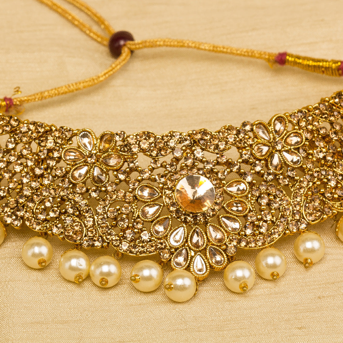 Front view grey background zoom photo showing bindhani golden -plated necklace featuring intricate traditional design with elegant pearl drop accents, detailed 