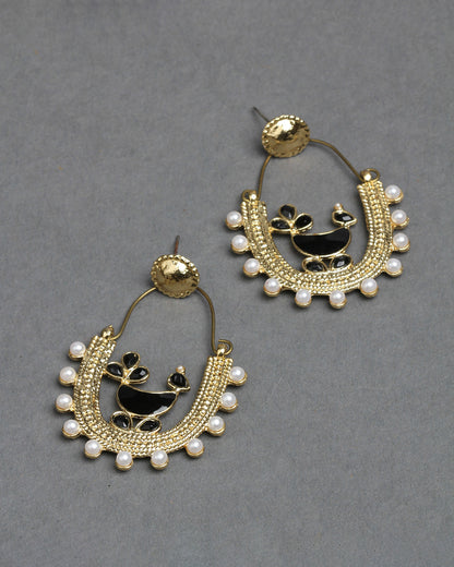 Bindhani gold-plated hoop earrings featuring a traditional peacock design with black enamel detailing at the center. The U-shaped earrings are decorated with intricate gold beadwork, white pearl drops along the outer edge, and a round textured stud top. Elegant handcrafted ethnic earrings displayed as a pair on a dark grey background.
