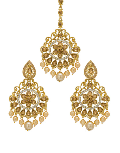 Bindhani gold-plated earrings and maang tikka set featuring antique gold-toned detailing, clear stones, and white pearl drop accents. The earrings showcase a floral center motif with intricate openwork filigree, teardrop-shaped stone detailing, and multiple pearl hanging drops with a larger center pearl. The matching maang tikka features a circular floral design with ornate filigree patterns and pearl drop embellishments. Front view displayed on a white background.