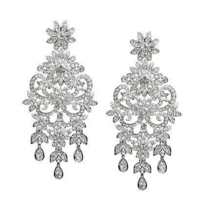 Bindhani silver-toned statement earrings featuring clear stones with sparkling crystal accents. Each earring showcases a floral top, intricate leaf and scrollwork detailing, a detailed central floral motif, and three dangling teardrop-shaped clear stone drops. Front view displayed on a white background.