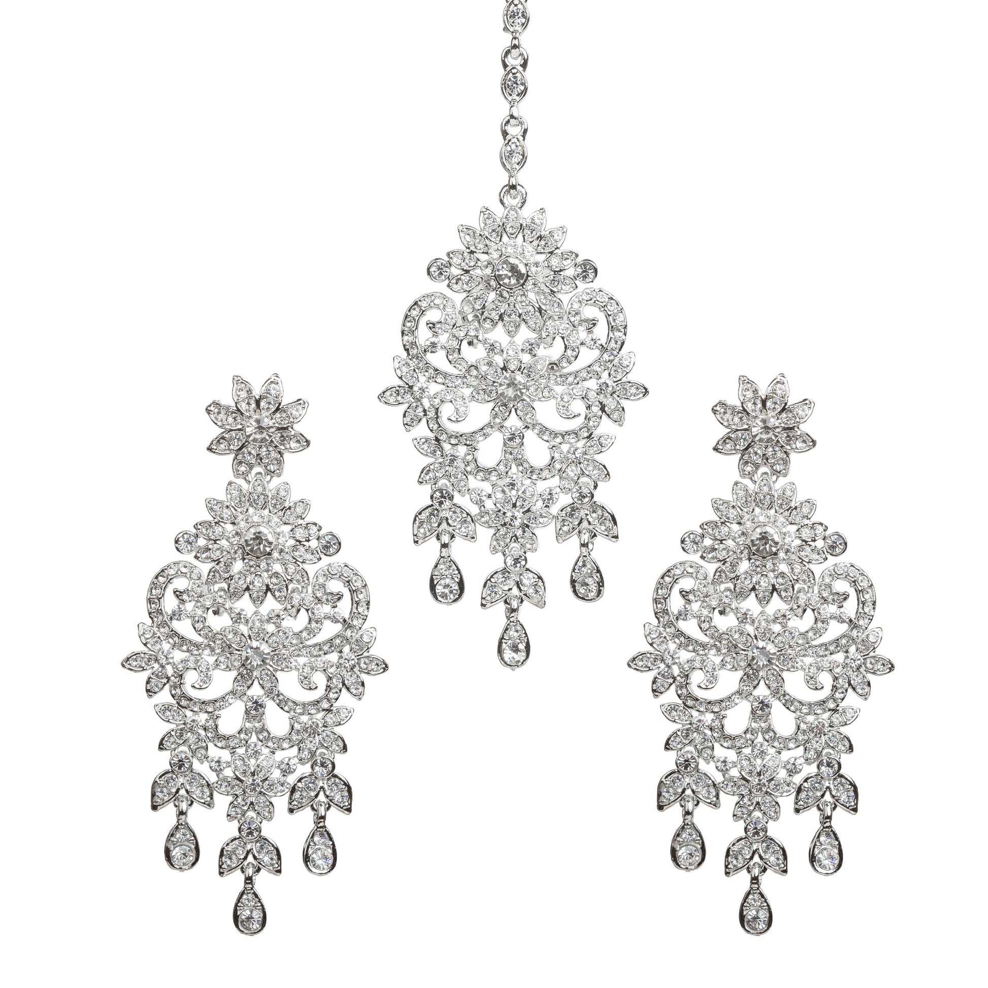 Bindhani silver-toned earrings and maang tikka set embellished with clear stones and sparkling crystal accents. The earrings feature a floral top, intricate leaf and scrollwork design with a central floral motif, and three dangling teardrop-shaped clear stone drops. The matching maang tikka showcases a coordinating floral design with detailed openwork, a central floral motif, and three dangling teardrop-shaped clear stone drops. Front view displayed on a white background.