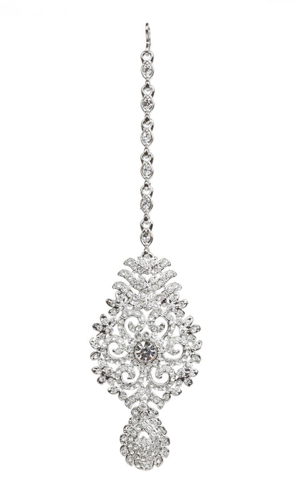 Bindhani silver-toned maang tikka featuring clear stones and sparkling crystal accents. The tikka showcases an intricate floral and leaf-inspired design with detailed scrollwork, a central round clear stone, and a teardrop-shaped stone-studded bottom drop. Front view displayed on a white background.