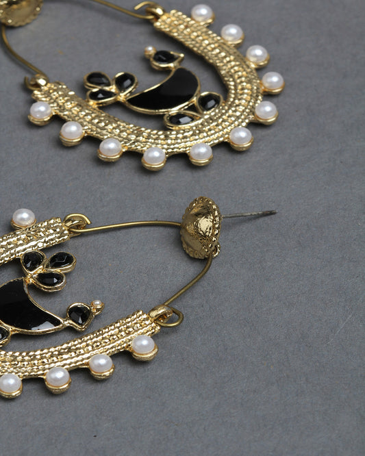 Close-up zoom view of Bindhani gold-plated peacock hoop earrings, showcasing the detailed black enamel peacock motif, fine gold beadwork texture, and evenly arranged white pearl drop accents around the curved design. The enlarged view highlights the intricate handcrafted traditional jewelry detailing.